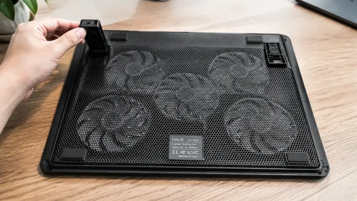 Close-up of a hand adjusting the two-position flip stand on the underside of the Havit cooling pad