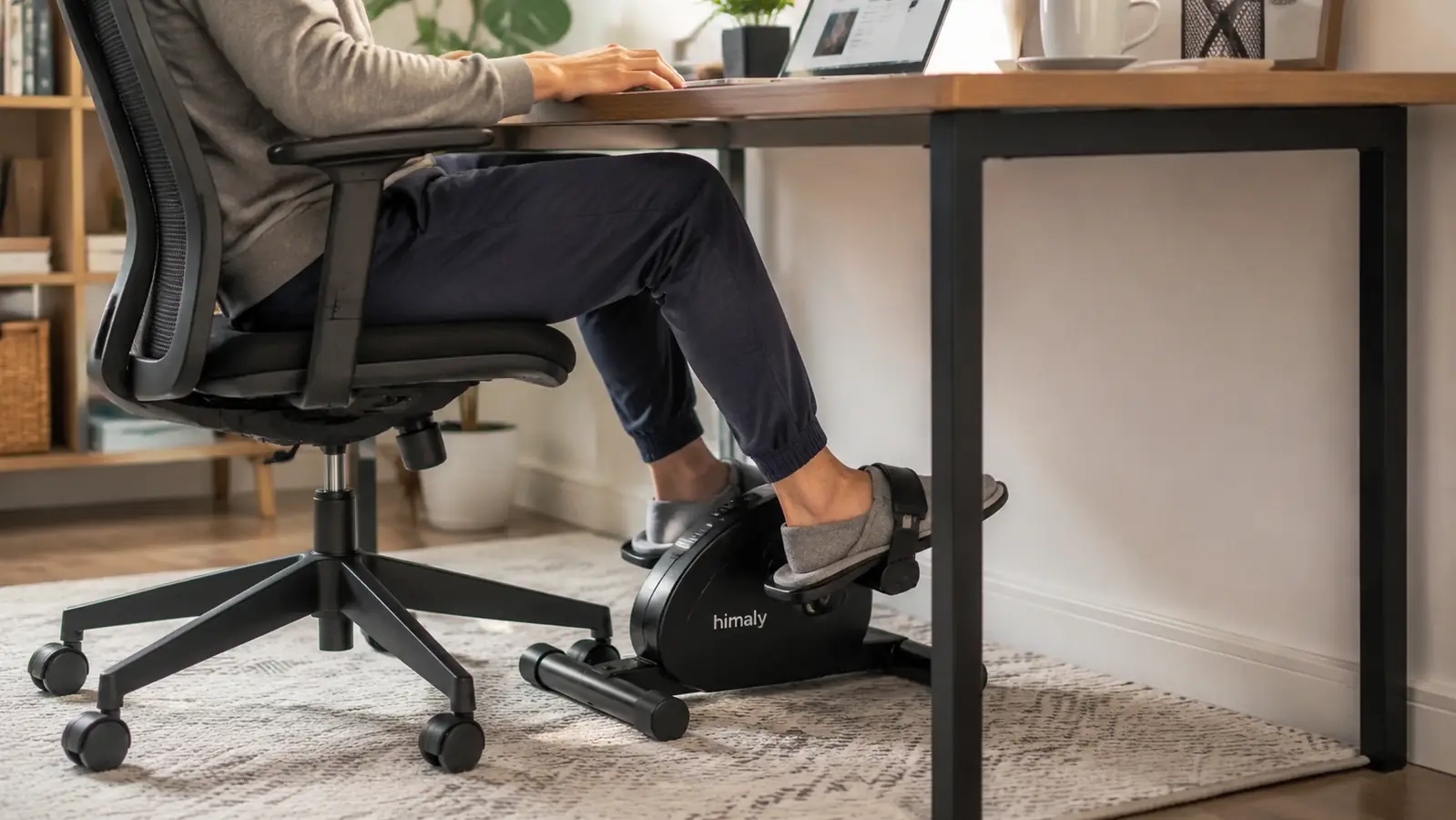 Person's feet resting on the pedals of an under-desk exerciser while typing on a laptop above
