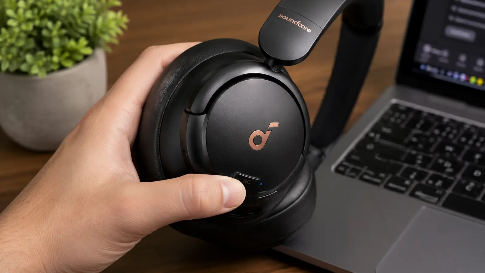 Hand adjusting the ANC mode button on the side of a pair of over-ear headphones before a call