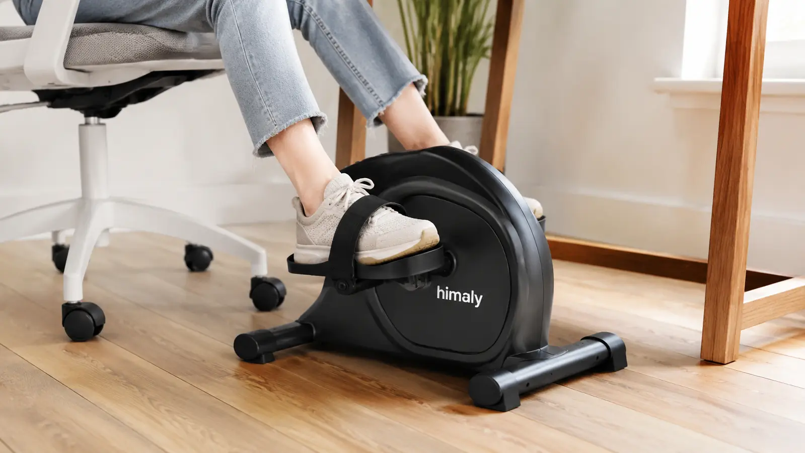 Close-up of feet pedaling the himaly under-desk exercise bike positioned beneath a home office desk